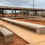 Praça Modelo do Guará em Brasília avançando após atrasos, com críticas à efetividade, em foto realista de construção urbana.