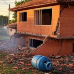 Residência danificada por explosão de botijão de gás em Ceilândia, com destroços e fumaça.