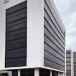 Mural de avisos em prédio público de Brasília com papéis de concurso, representando incertezas em resultados provisórios da Caesb.