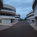 Prédio governamental fechado em Brasília contrastando com escritórios privados iluminados, destacando desigualdades entre setores.