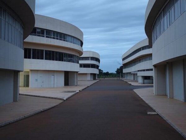 Prédio governamental fechado em Brasília contrastando com escritórios privados iluminados, destacando desigualdades entre setores.