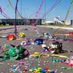 Rua em Brasília no Carnaval com confetes e máscaras abandonadas, expondo falhas no combate ao assédio.