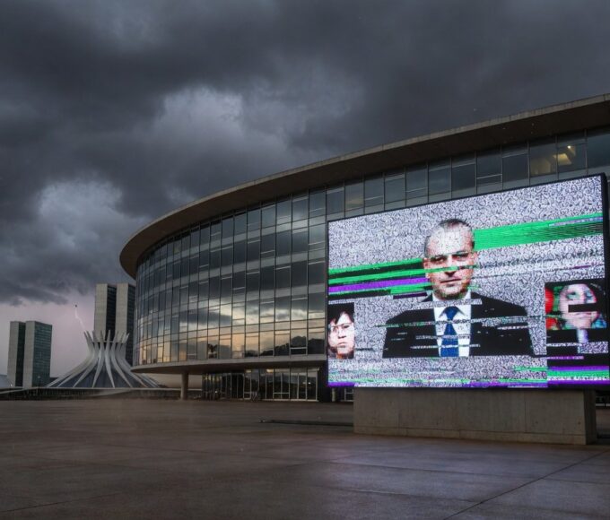 Edifício da CLDF em Brasília com tela de transmissão ao vivo com falhas, representando ineficiência e frustração dos cidadãos do DF.