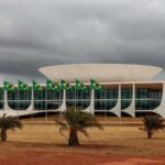 Fachada da CLDF em Brasília contrastando com hospital precário, simbolizando desperdício em homenagem ao CRO-DF e crises na saúde.