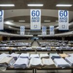 Auditório vazio na CLDF com banners dos 60 anos do CRO-DF e documentos ignorados de odontólogos, representando negligência.
