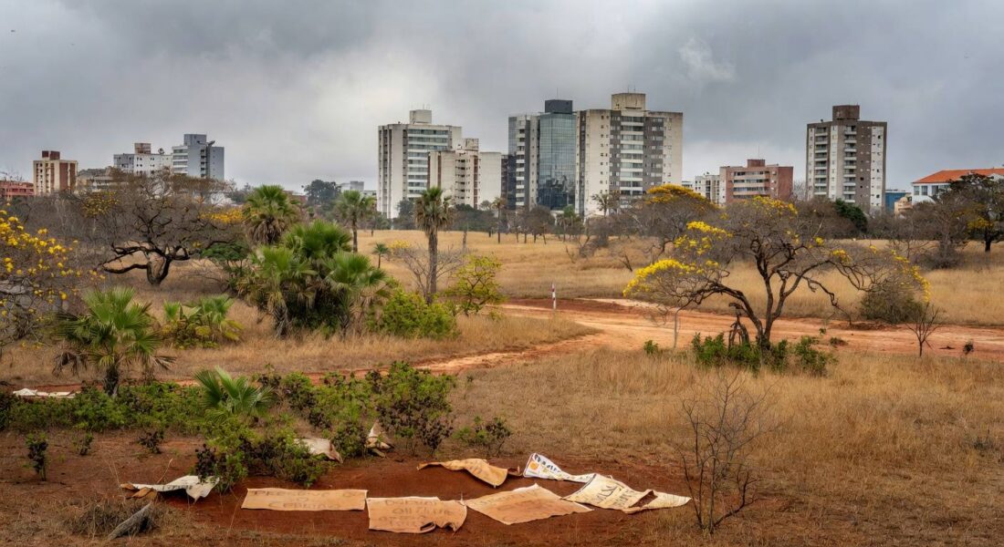 Reserva biológica no Guará ameaçada por pacote de salvamento do BRB, com faixas de protesto e vegetação do Cerrado.