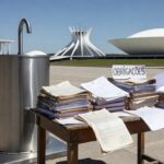 Bebedouro em evento em Brasília com documentos burocráticos, representando nova lei da CLDF sobre obrigações em eventos.