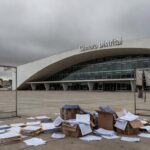 Edifício da Câmara Legislativa do DF em Brasília, com símbolos de homenagem e crises ignoradas, sob céu nublado.