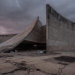 Edifício da CLDF em Brasília com documentos de seguros espalhados, representando homenagem polêmica e críticas por fraudes.