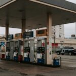 Posto de gasolina no Brasil com preços altos de combustíveis e viaturas da Polícia Federal, ilustrando investigação de aumentos abusivos.