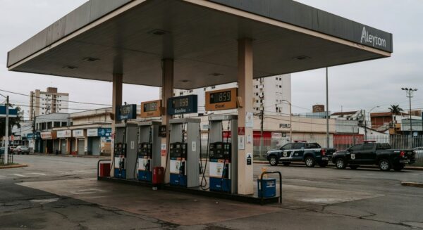 Posto de gasolina no Brasil com preços altos de combustíveis e viaturas da Polícia Federal, ilustrando investigação de aumentos abusivos.
