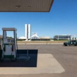 Posto de gasolina em Brasília com bombas de combustível e viaturas de fiscalização, ilustrando operação contra preços abusivos na gasolina.