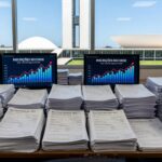 Mesa com notas fiscais e gráficos de inscrições no programa Nota Legal em Brasília, recorde de 1,6 milhão de participantes.