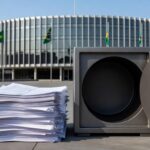 Edifício da CLDF em Brasília com documentos financeiros simbolizando reestruturação de carreira e sobrecarga nos cofres públicos.