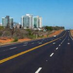 Nova via asfaltada em Arniqueira, Distrito Federal, com veículos transitando, beneficiando 50 mil motoristas.