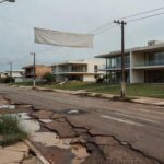 Rua no Park Way, Brasília, com decoração comemorativa e infraestrutura danificada, destacando negligência em soluções reais.