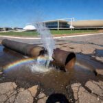 Tubulação de água com vazamento em rua de Brasília, ilustrando vulnerabilidades no abastecimento da Caesb no DF.