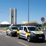 Rua em Brasília com sinalizações educativas de trânsito e veículo do Detran-DF, promovendo segurança viária.