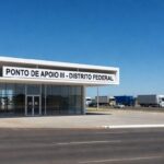 Edifício moderno de ponto de apoio a motoristas inaugurado pelo MTE no DF, com arquitetura de Brasília e rodovia ao fundo.